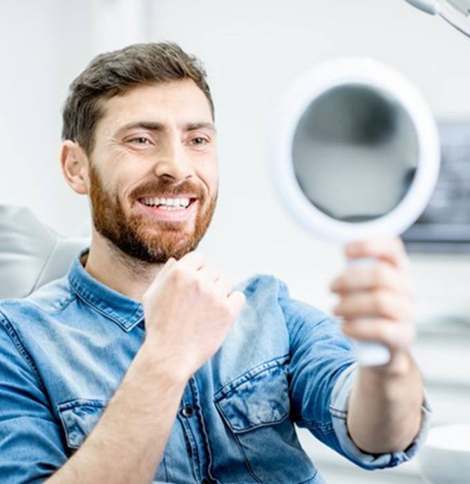 man seeing his new smile in dental mirror  