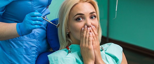 Woman in need of tooth replacement covering her mouth at the dental office