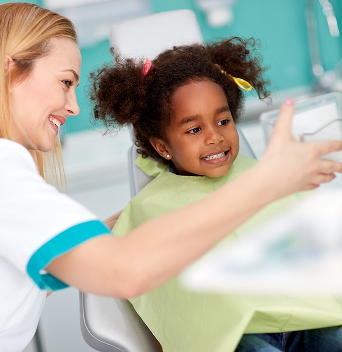 Little girl smiling at dentist after dental sealants