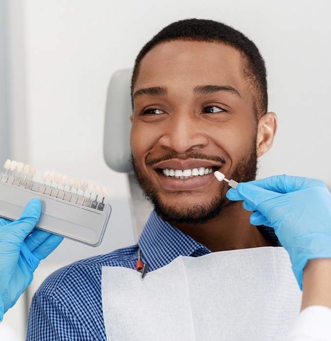 Man's smile compared with porcelain veneer shade chart