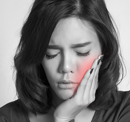 Woman in need of emergency dentistry holding cheek in pain