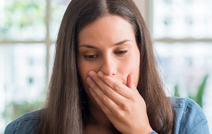 Woman with lost dental crown coveringher mouth