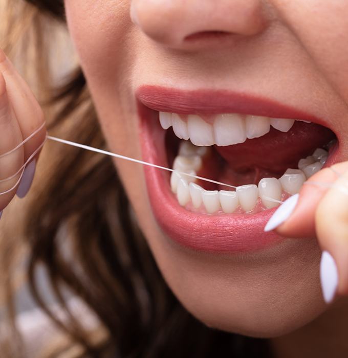 Patient flossing teeth to prevent dental emergencies