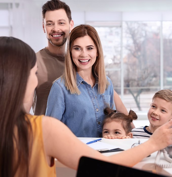 Family checking in at dental office reception desk