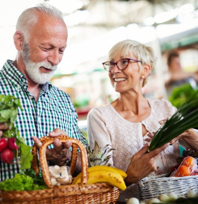 senior man and woman holding baskets of fruits and vegetables