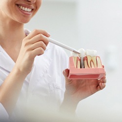 Dentist showing patient model of dental implants in Barton City, MI