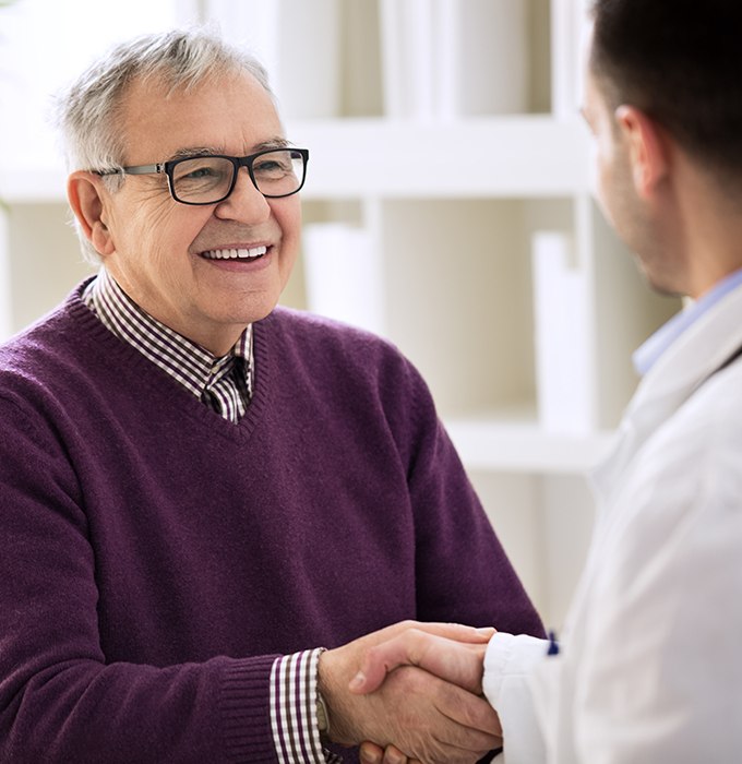 Man shaking hands with dentist during dental implant consultation