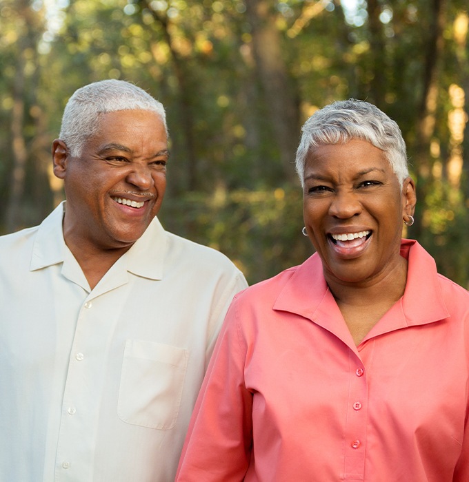 Man and woman smiling after dental implant tooth replacement