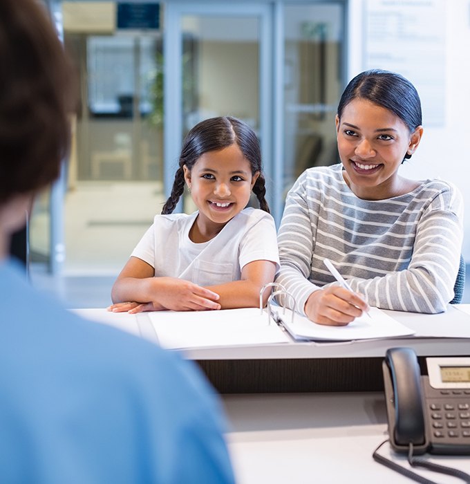 Mother and daughter checking in at dental office reception desk