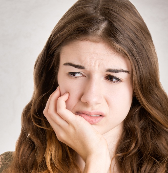 Woman in need of root canal therapy holding her jaw