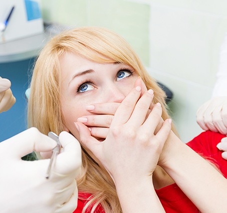 Fearful patient in need of sedation dentistry covering her mouth