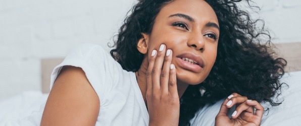 Woman in need of emergency dentistry holding cheek in pain