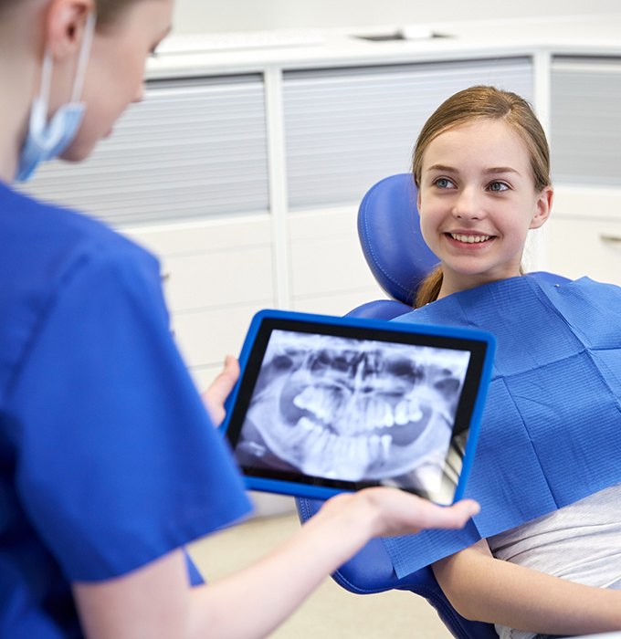 Dentist reviewing teen girl's digital dental x-rays