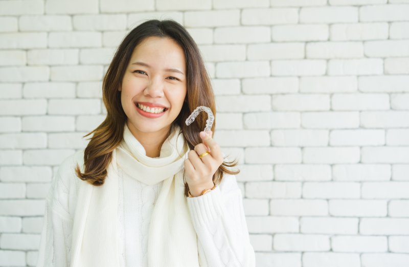 smiling person holding Invisalign