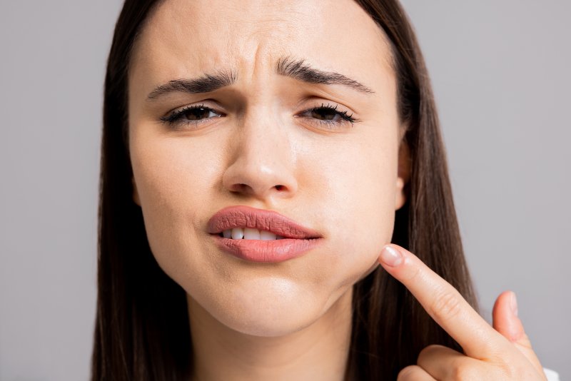 A closeup of a woman pointing out her dental emergency