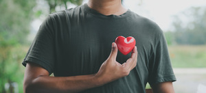 Man in grey shirt holding heart to represent heart health