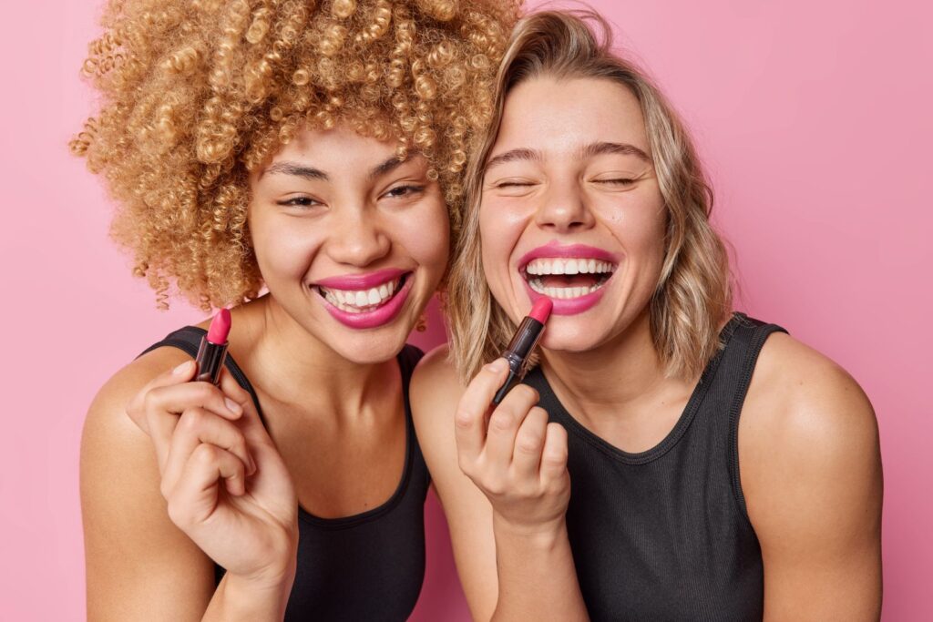 Two women trying on lipstick